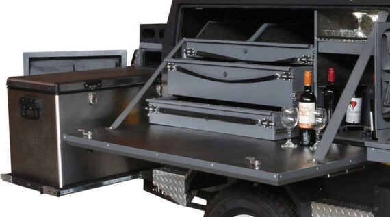 Conqueror Compact Platinum Edition with refrigerator, half-opened drawers, and wine bottle with glasses.